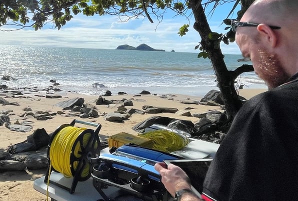 underwater drone on beach with double island in background and technician with tablet in foreground