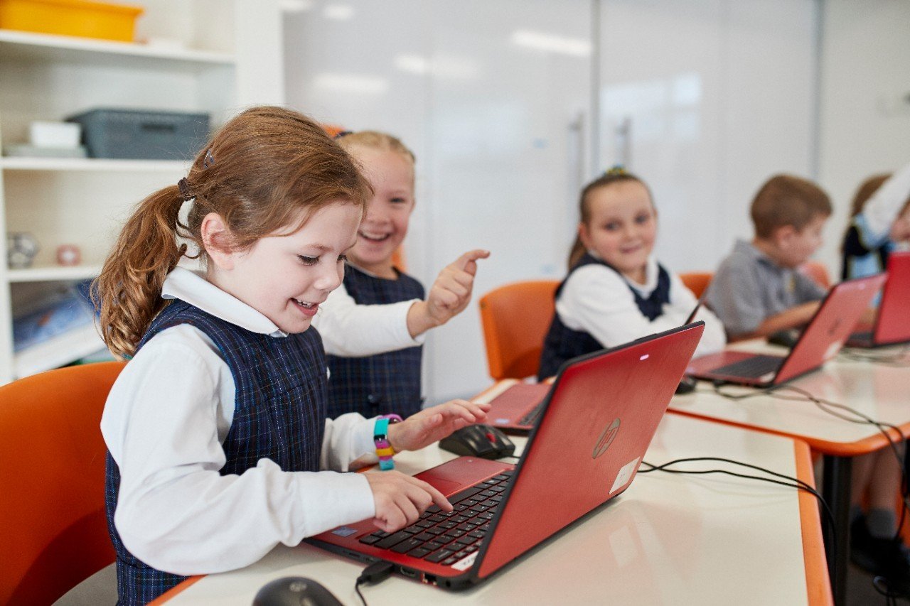 education - primary girls laughing with laptop
