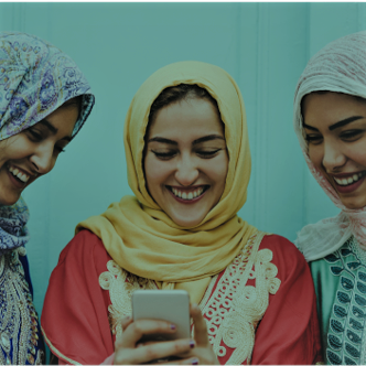 three women with headscarves using mobile phone